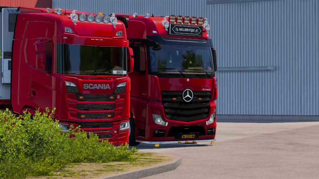 Red Scania and Actros parked side by side — fleet duo
